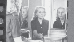 The banner features a black-and-white photograph of a woman seated before a three-panel mirror, showing her face from multiple angles. A filmstrip border appears along the left edge of the image.